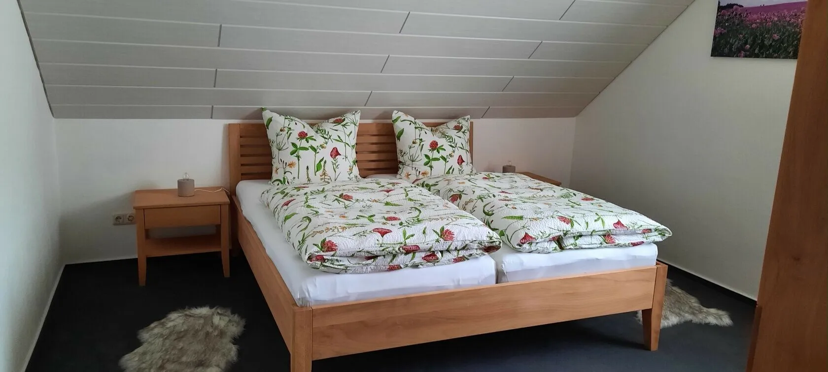 Schlafzimmer mit Doppelbett aus hellem Holz und zwei Nachttischen.