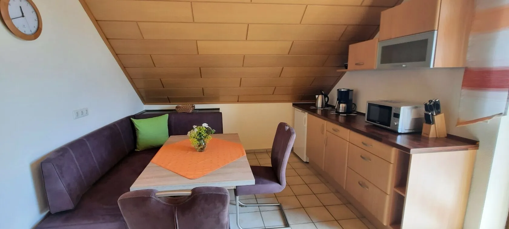 Essplatz in der Küche mit Eckbank, daneben Kaffeemaschine, Mikrowelle und Toaster.